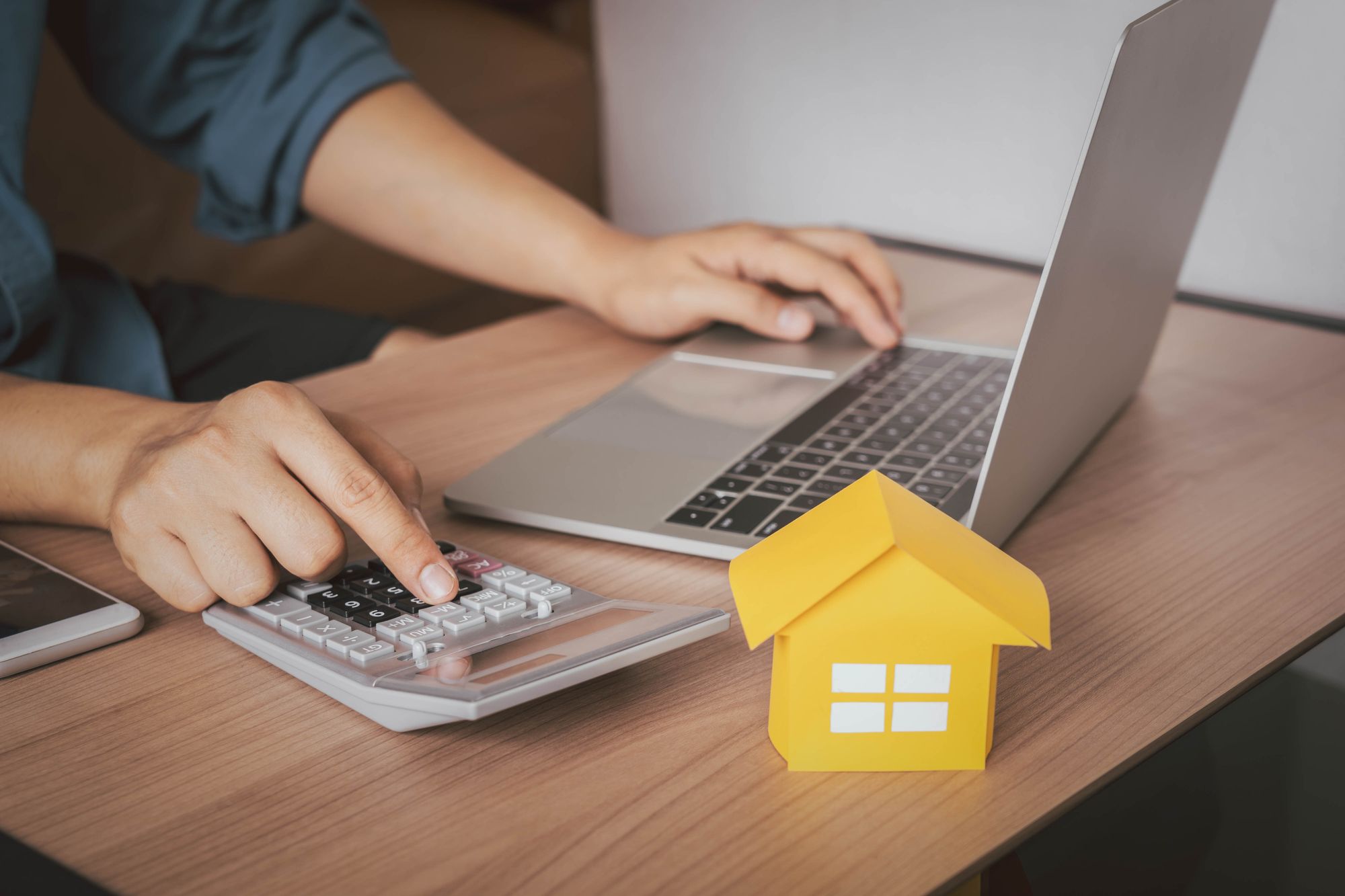 A home buyers uses a laptop and calculator to determine what they're closing costs will be.