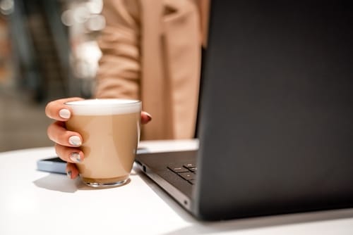 Real estate agent drinking coffee and efficiently working on her laptop